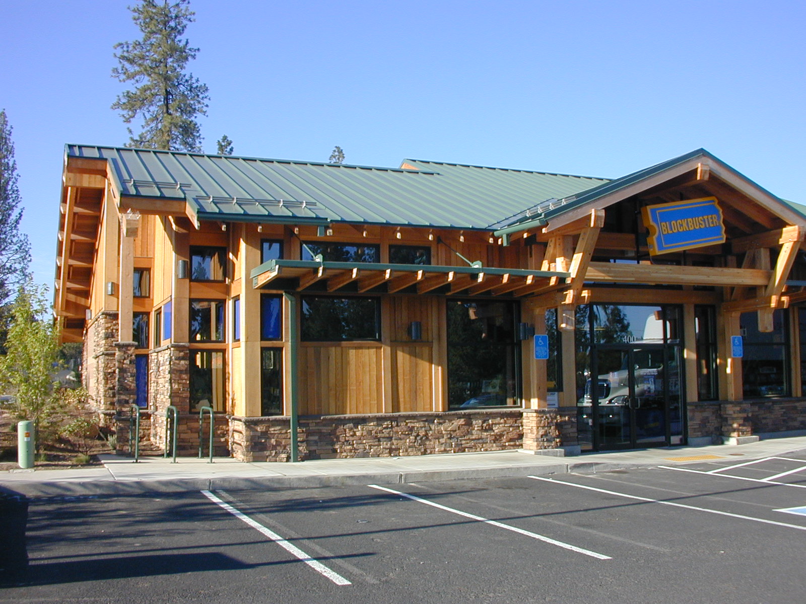 Blockbuster store featuring a rustic wooden exterior and green roof, set in a spacious parking lot.