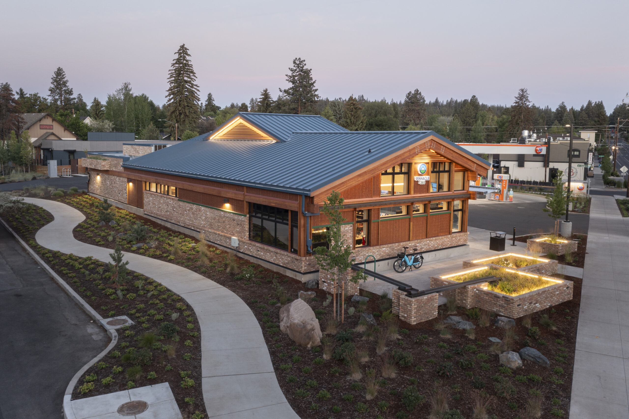 Modern building with large windows and wooden accents, surrounded by landscaped paths and greenery, serving as a community hub.
