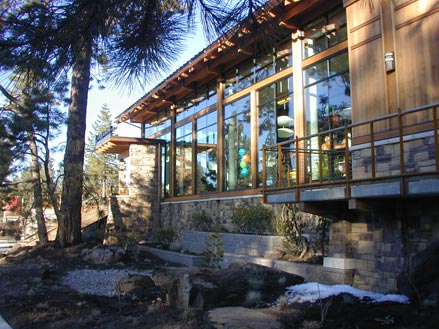 Modern architectural building with large windows, surrounded by trees and landscaped stones